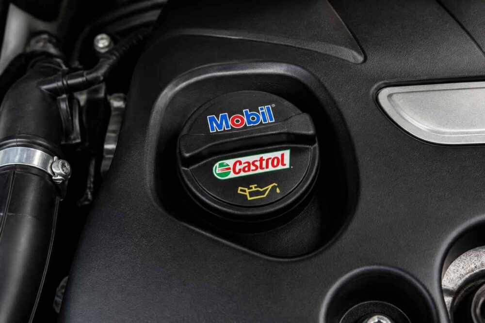 Korek wlewu oleju z oznaczeniami Mobil i Castrol na pokrywie silnika samochodowego