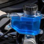 Przezroczysty niebieski zbiorniczek płynu hamulcowego przy kierownicy motocykla