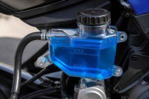 Przezroczysty niebieski zbiorniczek płynu hamulcowego przy kierownicy motocykla