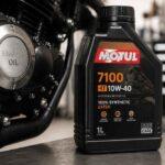 Butelka oleju Motul 7100 10W-40 ustawiona obok silnika motocyklowego