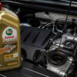 Butelka oleju Castrol 5W-40 stojąca obok otwartego wlewu oleju silnikowego