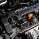Zbliżenie na silnik Honda z czarną pokrywą zaworów i pomarańczowym wskaźnikiem oleju