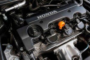 Zbliżenie na silnik Honda z czarną pokrywą zaworów i pomarańczowym wskaźnikiem oleju