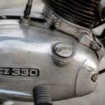 Zbliżenie srebrnego silnika motocykla z oznaczeniem CZ 330 i chromowanym wydechem