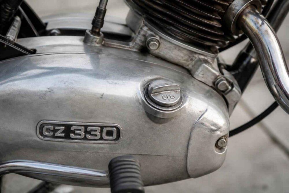 Zbliżenie srebrnego silnika motocykla z oznaczeniem CZ 330 i chromowanym wydechem