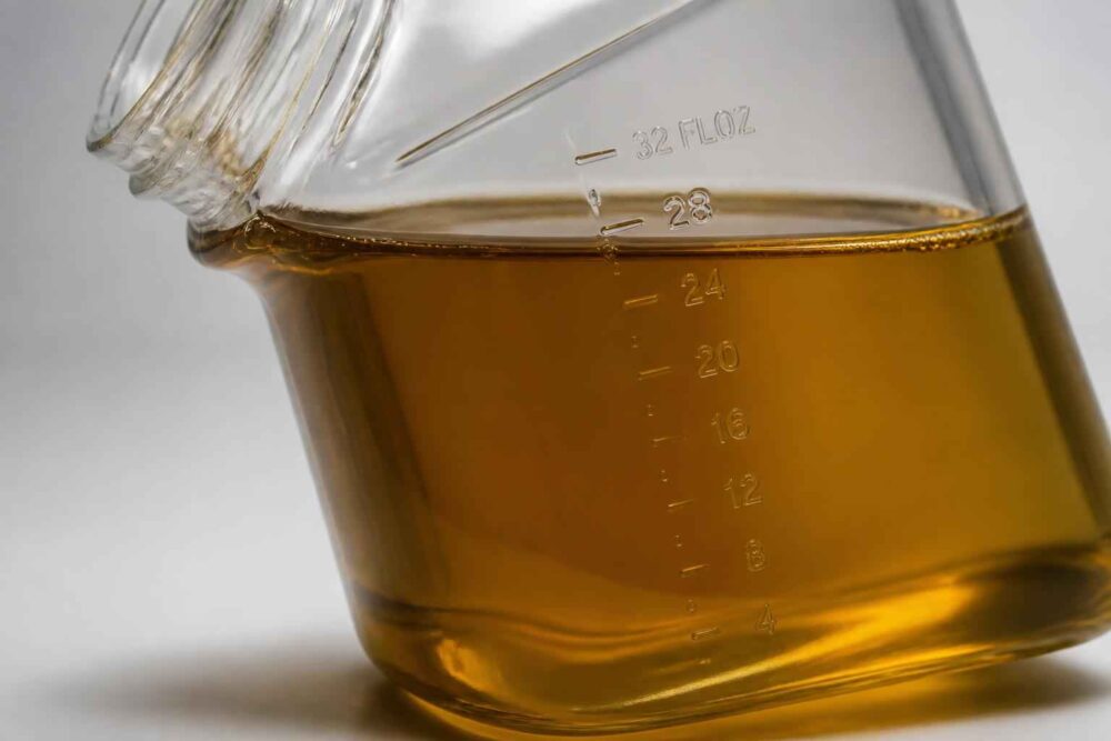 Szklana kolba laboratoryjna z podziałką, wypełniona przezroczystym bursztynowym roztworem