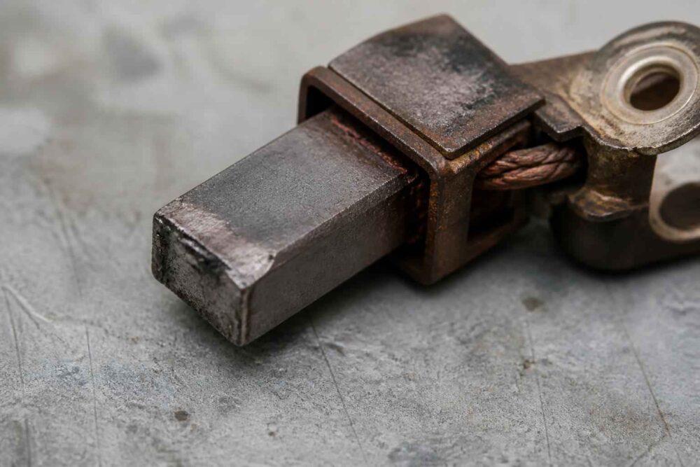 Zardzewiały metalowy element z prostokątnym trzpieniem na szarym blacie roboczym
